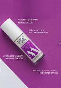 Weiße zylindrische Flasche mit einem lila Etikett und klarem Deckel. Enthält 30 ml Serum; enthält Texte über Hautvitalität und Kollagenunterstützung.