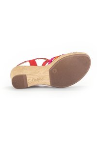 Sandale multicolore avec un talon en liège, semelle en caoutchouc et brides dans des teintes rouge, rose et orange. Texture lisse avec une base anti-dérapante.