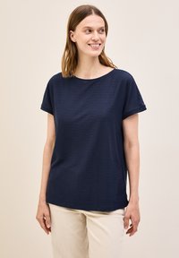 Top de manga corta azul marino con textura acanalada, corte relajado y cuello redondo, combinado con pantalones beige claros.