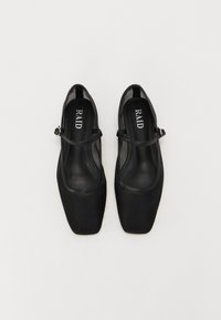 Chaussures noires à bout carré avec un dessus en tissu texturé et une fine bride de cheville, dotées d'une petite boucle. L'intérieur est lisse avec un logo.