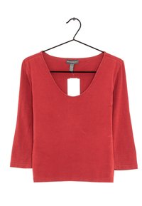 Červený top s dlouhým rukávem a hlubokým výstřihem ve tvaru V, vyrobený z měkkého materiálu. Obsahuje štítek visící z výstřihu. Jednoduchý design bez vzorů.