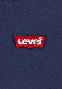 Camiseta de algodón azul marino con un parche de logo Levi's bordado en rojo en el pecho. Textura suave, ajuste regular, sin detalles adicionales.