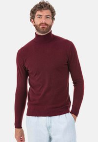 Bordeauxroter Rollkragenpullover aus Strickstoff mit langen Ärmeln sowie gerippten Bündchen und Saum. Er zeichnet sich durch eine enge Passform und eine glatte Textur aus.