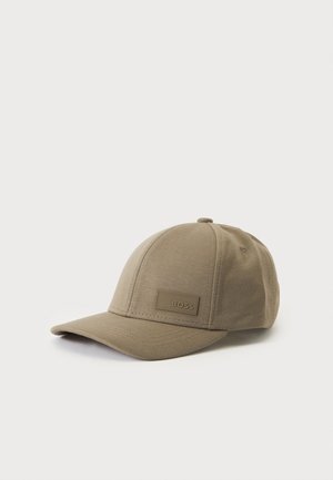 Beige stof baseballkasket med buet skygge og en rektangulær lap mærket "BOSS" på frontpanelet, vist på en hvid baggrund.