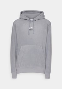 Grå hoodie med kenguruficka, dragsko till huvan och en Nike Air-logotyp i kontrasterande vitt på bröstet. Mjuk textur, avslappnad design.