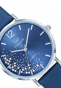 Montre à quartz avec un cadran métallique bleu et des aiguilles en argent. Bracelet en cuir bleu profond. Caractéristiques d'accents scintillants près du bas.