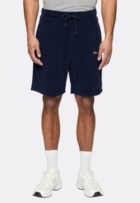Pantaloni corti in cotone blu navy con vita elastica e cordoncino, dotati di un piccolo logo dorato sulla coscia sinistra e una vestibilità comoda.