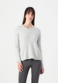 Light gray knitted sweater with a V-neck, ribbed texture, and long sleeves, paired with dark gray slim-fit jeans.