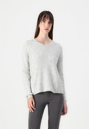 Pull en tricot gris clair avec un col en V, texture côtelée et manches longues, associé à un jean slim gris foncé.