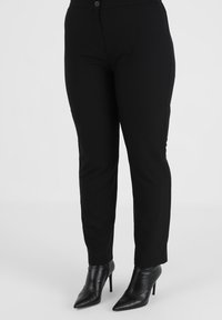 Sorte skræddersyede bukser med slim fit, der har en glat overflade og en knaplukning ved taljen. Båret med spidse sorte hæle.