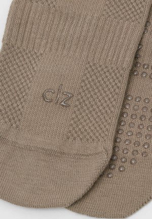 Calcetines marrones de punto con patrones texturizados, un logo "clz" y agarres de puntos de goma en la suela para mayor tracción. Tejido suave y liso.