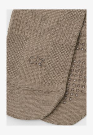 Bruine gebreide sokken met getextureerde patronen, een logo "clz" en rubberen stippen voor grip op de zool. Zacht, soepel materiaal.