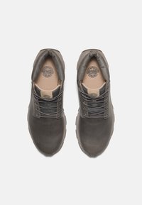 Zapatos de cuero gris con una superficie texturizada, punta redonda, cordones y un collar acolchado. Presenta una plantilla de color marrón y una suela duradera con patrón.