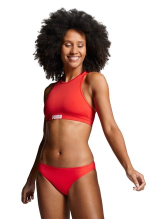 Czerwony sportowy zestaw bikini z topem na wysokiej szyi i niskim stanem. Wykonany z gładkiego, elastycznego materiału. Posiada biały logo z przodu.