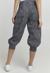 Svart och vitmönstrade byxor med avslappnad passform, elastisk midja och rynkade muddar, i kombination med vita sneakers.