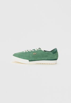 Green suede low-top sneaker with white sole and laces, featuring a Lacoste crocodile logo on the side.