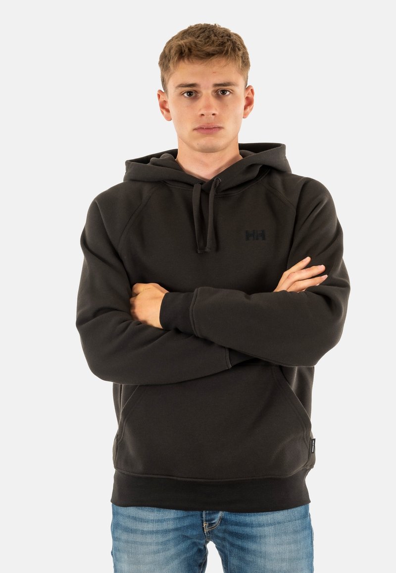 Zwarte hoodie met een gestructureerde afwerking, kangoeroezak en geborduurd logo; gecombineerd met blauwe denim.