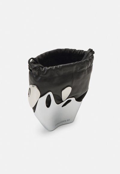 Geantă bucket din piele neagră, cu o deschidere gathered, accesorii din metal argintiu și o bază metalică elegantă cu forme tăiate și text.