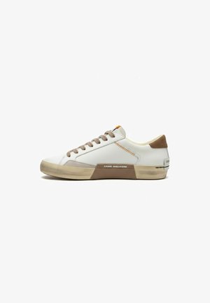 Sneaker bianco basso con lacci beige e suola beige, toppa marrone sul tallone e scritta "CRIME SNEAKERS" sul pannello laterale della suola.