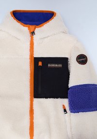 Giacca in fleece bianca con zip arancione, tasca sul petto nera e dettagli blu sul colletto e sulle maniche. Presenta un'etichetta con logo sul braccio.