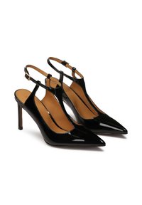 Mustast patendnahast slingback-kontsaga kingad terava ninaga ja õhukeste kõrgete kontsadega. Omab T-riba disaini ja reguleeritavaid pahkluu pandlaid.