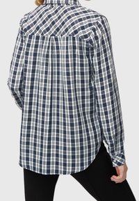 Camicia a quadri blu navy e bianca con maniche lunghe, polsini con bottoni e dettaglio sulla spalla posteriore. Realizzata in un tessuto intrecciato con vestibilità comoda.