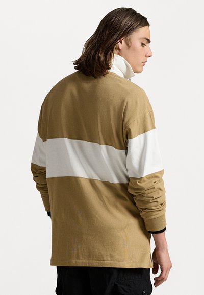 Beige langslavende shirt met een witte horizontale streep. Heeft een relaxte pasvorm, geribde manchetten en een gestructureerd katoenmateriaal.