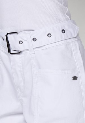 White pants made of cotton with a wide waistband, black metal buckle, and silver eyelets. Features side pockets and a logo detail.