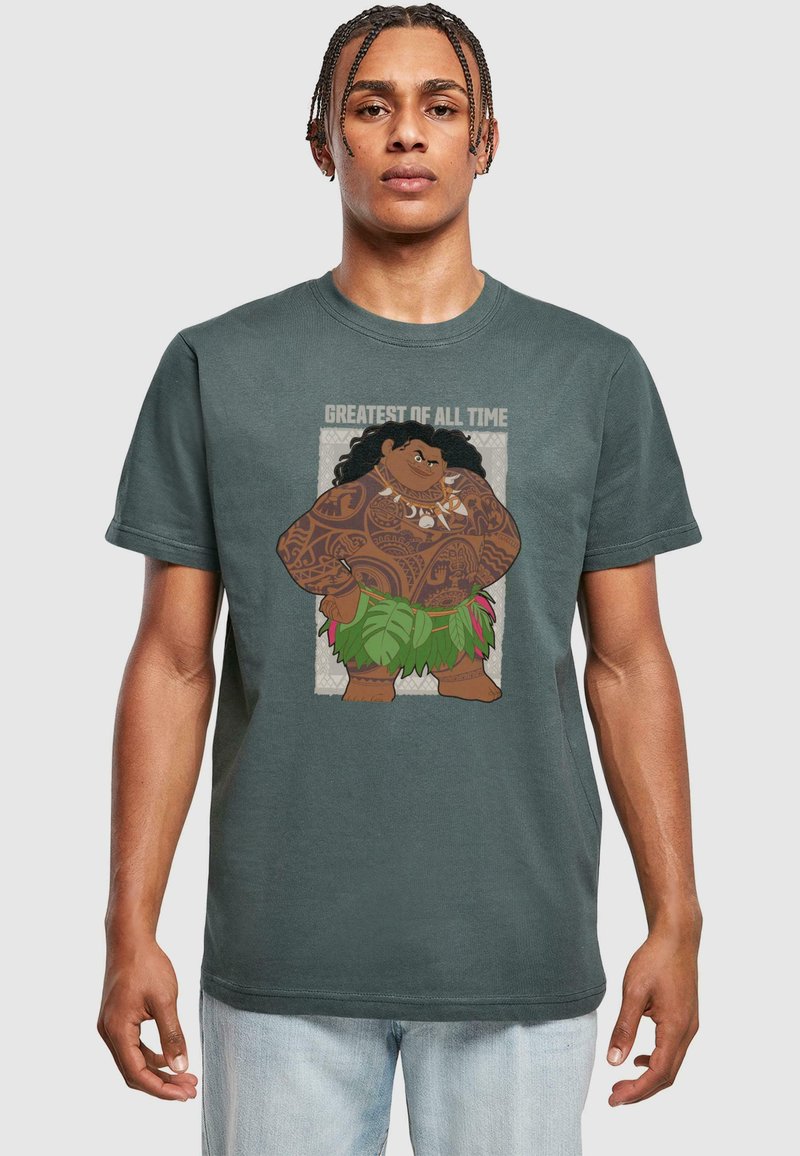 Dark green t-shirt featuring a graphic of a fictional character with intricate tattoos, wearing a leaf skirt, with the text "GREATEST OF ALL TIME."