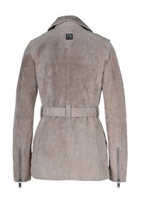 Veste en daim beige vue de dos, avec une ceinture à la taille, des détails zippés sur les manches et un petit patch logo carré sous le col.