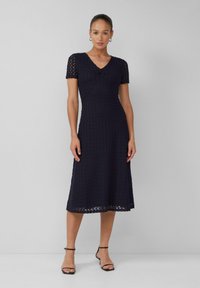 Robe midi en dentelle bleu marine avec des manches courtes, un décolleté en V, un corsage ajusté et une jupe évasée. Motif texturé et taille bien marquée.