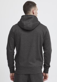 Donkergrijze hoodie van zachte stof. Bevat een capuchon met trekkoord, ribgebreide manchetten en een eenvoudige uitstraling zonder zichtbare logo's of patronen.