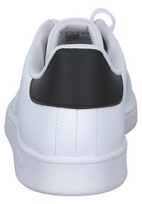 Zapatilla blanca con un acento en el talón de cuero negro, parte superior de sintético suave, suela texturizada y detalles cosidos en el talón y los lados.