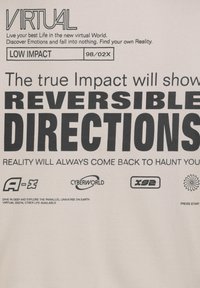 Light beige fabric features bold black text with phrases like "VIRTUAL," "LOW IMPACT," and "REVERSIBLE DIRECTIONS," along with various logos below.