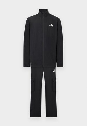 Schwarzer zweiteiliger Trainingsanzug mit Reißverschlussjacke und Cargohose, beide mit kleinen weißen diagonalen Streifenlogos auf Brust und Oberschenkel.