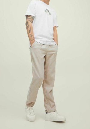 Wit T-shirt met palmboomprint, gecombineerd met lichtbeige broek en witte sneakers, met een casual, ontspannen pasvorm.