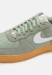 Zöld nubuk és bőr sneaker perforált orral, fehér swoosh logóval és világosbarna gumis HR. Textúrázott fűzőkkel és részletekkel rendelkezik.