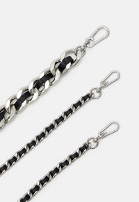 Bandoulières en métal et cuir noir avec chaîne en trois longueurs, dotées de ferrures argentées brillantes et de divers designs de maillons. Crochets pour fixation inclus.