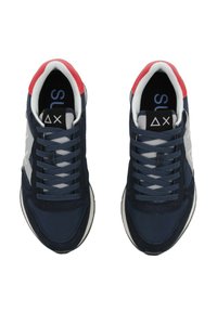 Zapatilla azul marino con acentos blancos, que presenta un upper texturizado, cuello acolchado y cordones planos. Detalles rojos en el talón y logo visible.