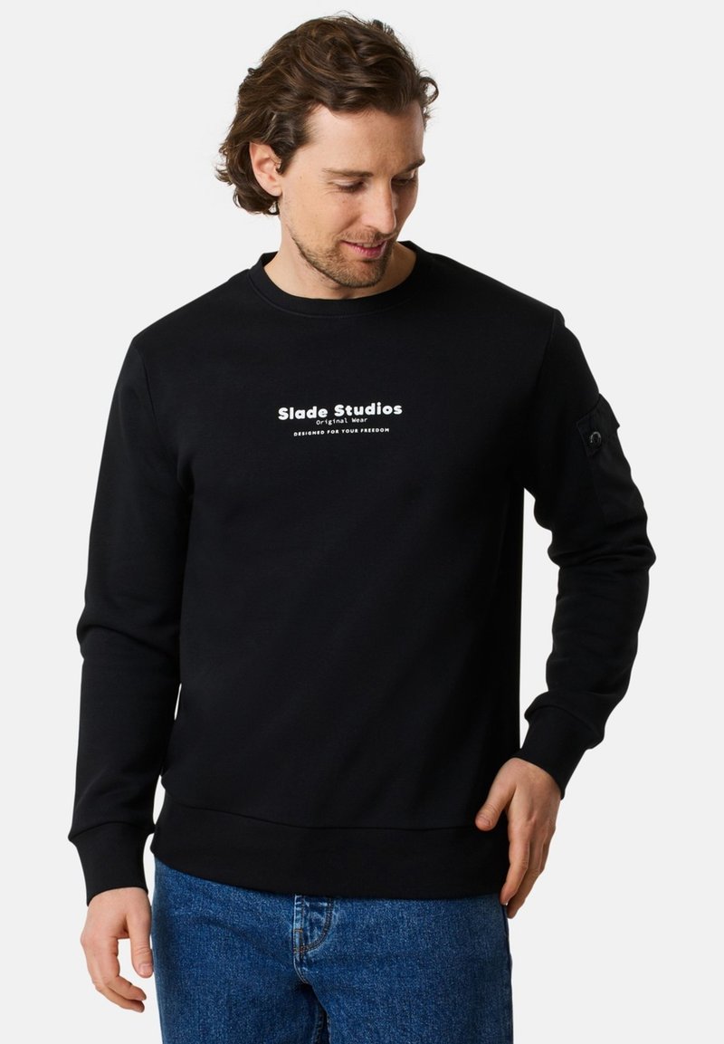 Svart sweatshirt med rundad halsringning, prydd med vit tryckt text på bröstet och en sidoficka med knappdetalj. Texturerad tyg.
