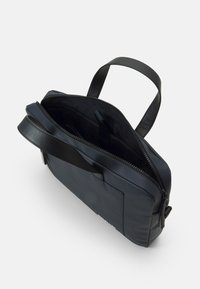 Borsa blu navy realizzata in tessuto testurizzato con chiusura a zip, manico corto e tasca esterna. L'interno è foderato con un materiale liscio.