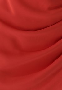 Punane kangas, millel on sile, tekstureeritud pind, millel on kerge langevus ja voldid, rõhutades selle rikast värvi ja ühtlast viimistlust.