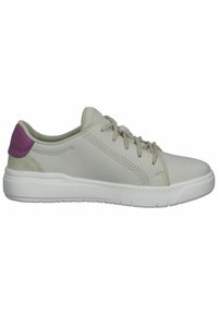 Ljust beige sneaker med en vit sula, med en strukturerad yta, grå snören och en lila accent på hälen. Minimalistisk design.
