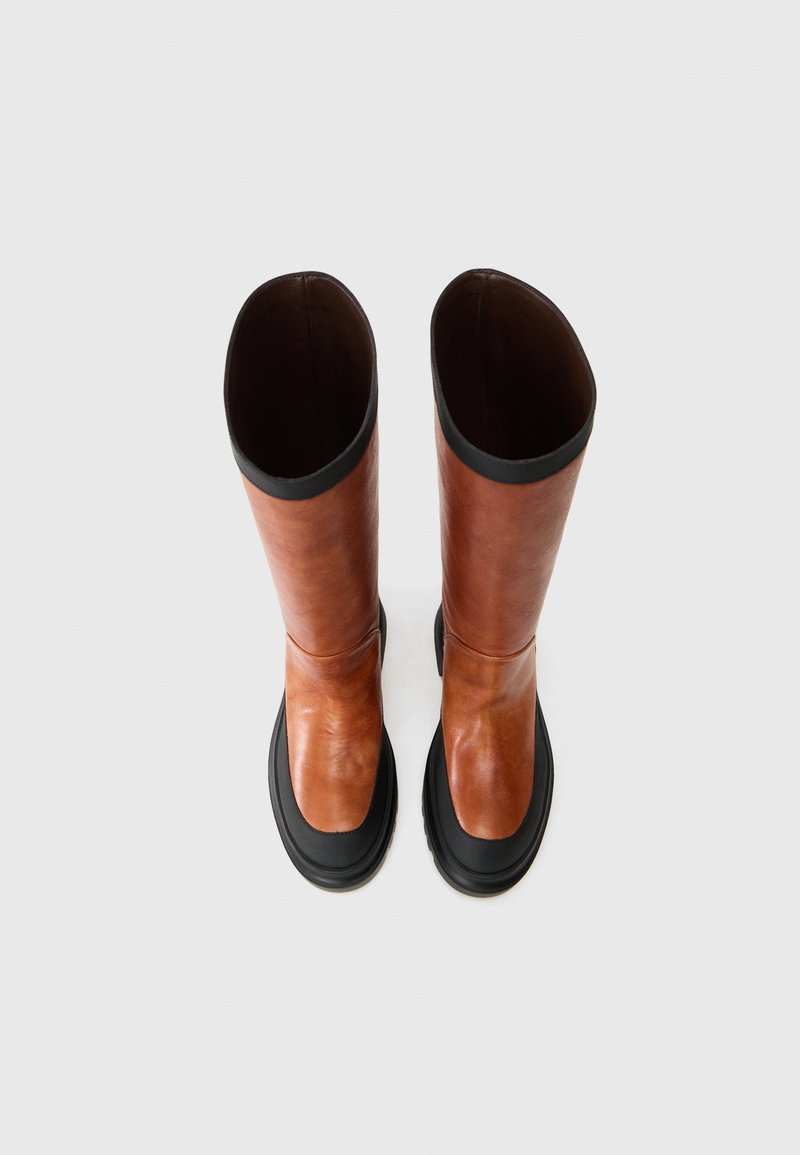 Brune læder knæhøje støvler med en sort gummisål. Glat tekstur, afrundet form og åbent design. Minimalistisk stil.
