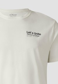 T-shirt s.Oliver ivoire avec texte noir "Let's Unite Interconnect and Synergize" sur le côté gauche de la poitrine, col rond, manches courtes.