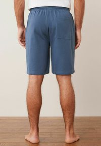 Blaue Baumwollshorts mit einem elastischen Bund und einer Gesäßtasche, mit glatter Textur und geradem Schnitt, von hinten gezeigt.