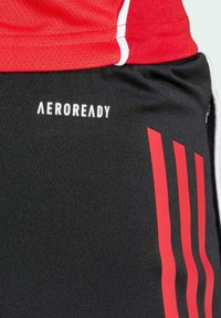 Black athletic shorts with red stripes, made of textured fabric. Features "AEROREADY" logo in white on the left leg.
