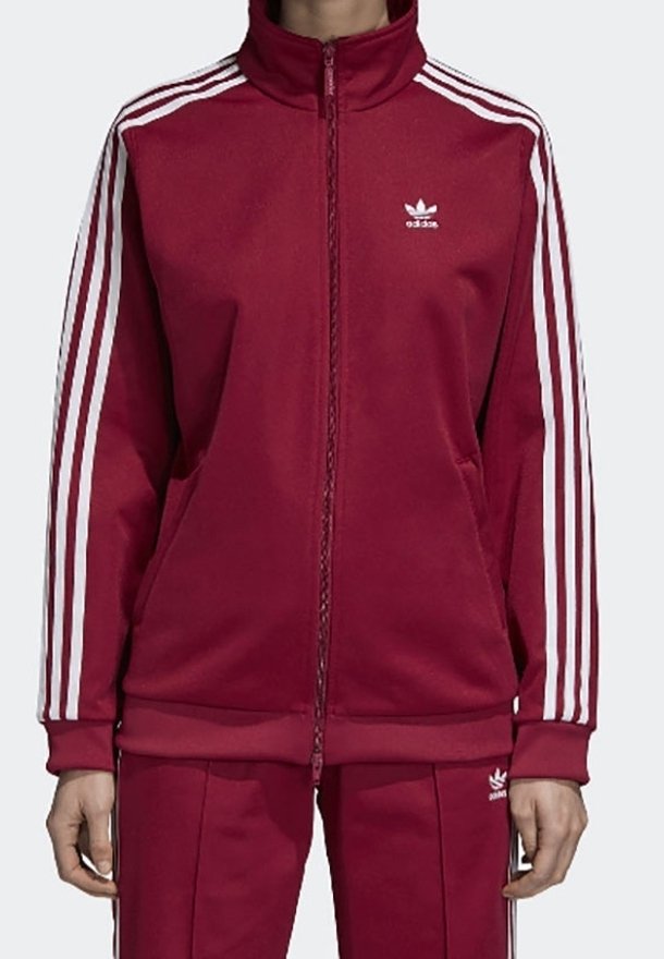Rote Trainingsjacke mit weißen Streifen an den Ärmeln, hohem Kragen und Reißverschluss vorne; aus strukturiertem Stoff gefertigt; mit kleinem weißen Logo auf der Brust.