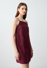 Bordeaux linnen slipdress met dunne bandjes, een rechte halslijn en een losse pasvorm. Heeft een subtiele textuur en een schone zoom.