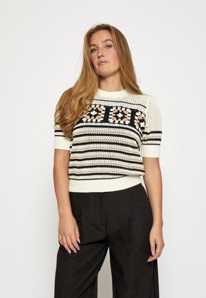 Kurzarmpullover in Creme mit schwarz-beigem Streifenmuster. Verfügt über eine Häkelstruktur und einen festen gerippten Saum. Schlichte schwarze Hohe-Taillenhose.